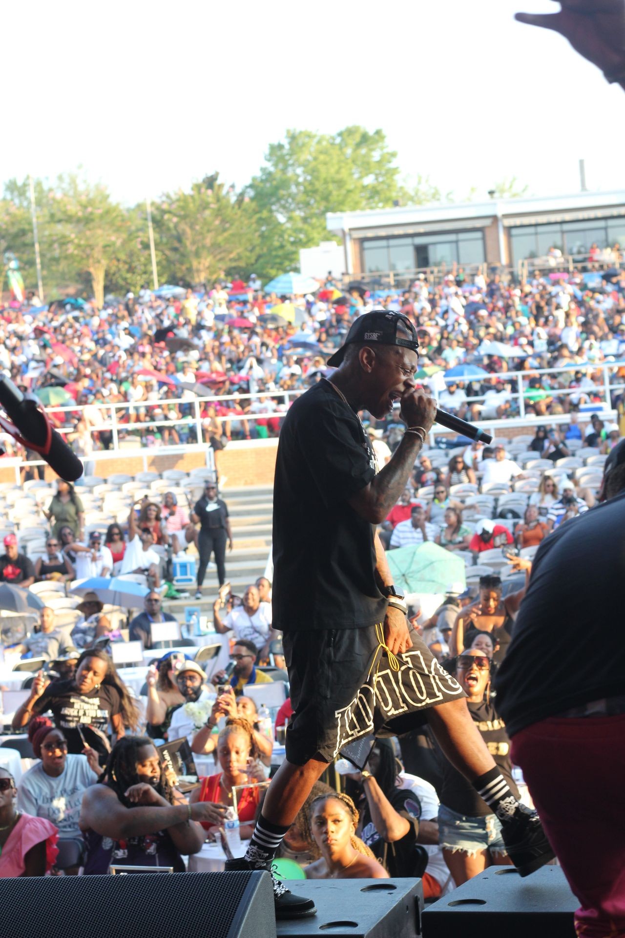 rapper holding mic onstage outdoors